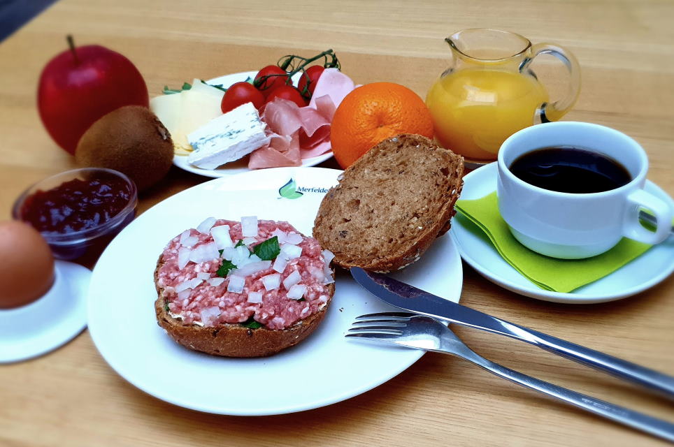Teller mit Mettbrötchen und Tasse Kaffee